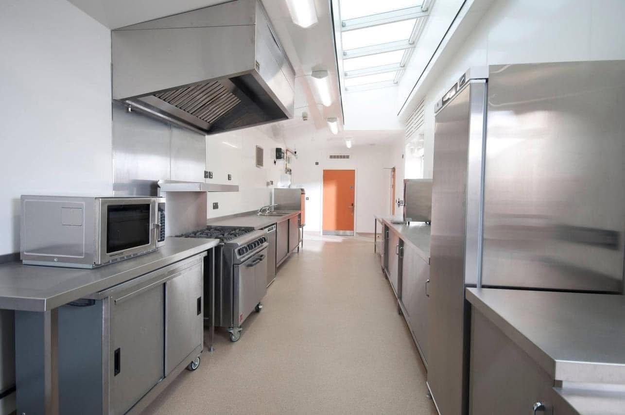 Commercial kitchen with stainless steel cookers, oven, microwave and fridges
